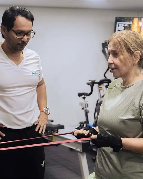 Paciente adulto mayor haciendo entrenamiento de fuerza con banda elástica en MOVID