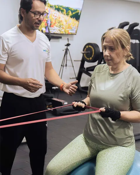 Paciente adulto mayor trabajando equilibrio con pelota y banda elástica en MOVID